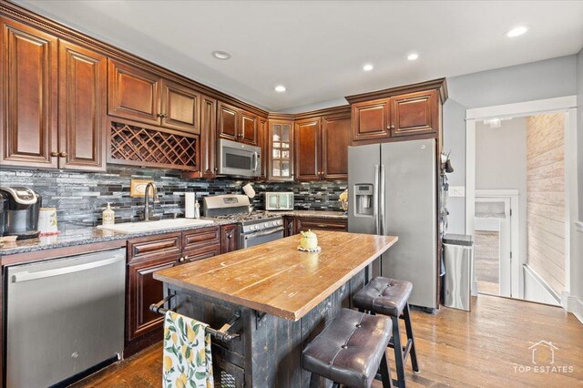 309 E Elm St, Villa Park, IL 60181 - kitchen featuring a kitchen breakfast bar, tasteful backsplash, wood finished floors, a sink, and stainless steel appliances