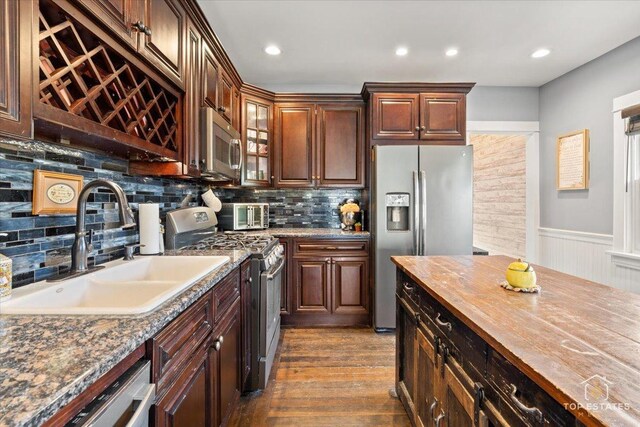 309 E Elm St, Villa Park, IL 60181 - kitchen featuring decorative backsplash, a sink, a wainscoted wall, dark wood-style floors, and stainless steel appliances