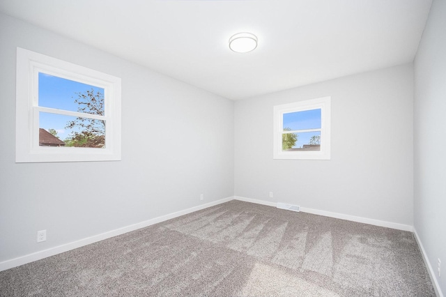 carpeted empty room featuring baseboards and visible vents