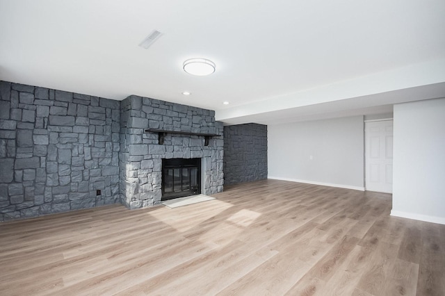 unfurnished living room with baseboards, visible vents, wood finished floors, and a fireplace