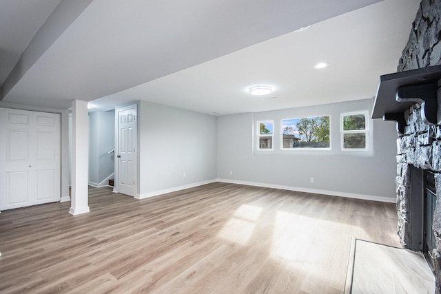 unfurnished living room with baseboards, wood finished floors, stairway, and a fireplace