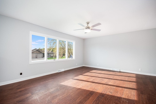 unfurnished room with baseboards, a ceiling fan, dark wood finished floors, and visible vents
