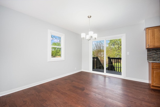 unfurnished dining area with baseboards, a notable chandelier, dark wood-style floors, and visible vents