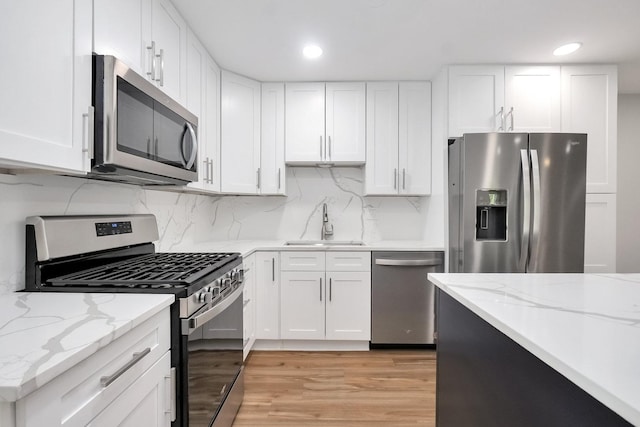 7330 Fairview Ave Unit 104, Downers Grove, IL 60516 - kitchen featuring white cabinets, tasteful backsplash, a sink, light wood finished floors, and appliances with stainless steel finishes