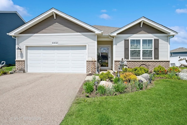 ranch-style house featuring a garage, brick siding, driveway, and a front yard