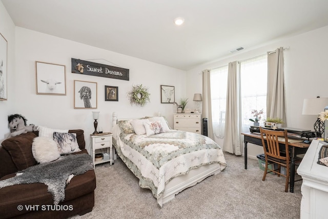 bedroom featuring light carpet and an office area