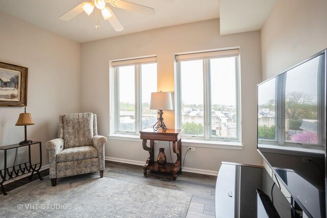 sitting room with baseboards, ceiling fan, and wood finished floors