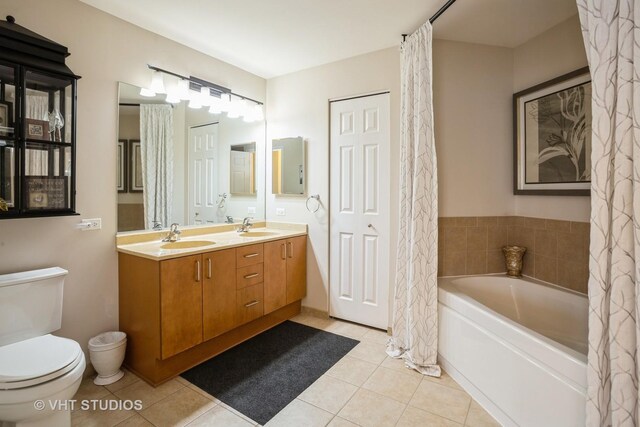 bathroom featuring double vanity, toilet, a bath, tile patterned floors, and a sink