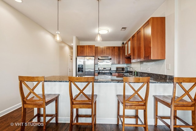 521 N Racine Ave Unit 3, Chicago, IL 60642 - kitchen featuring stainless steel appliances, under cabinet range hood, a peninsula, dark stone countertops, and brown cabinets