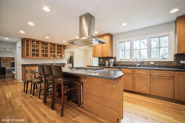 3935 Russett Ln, Northbrook, IL 60062 - kitchen featuring a breakfast bar, light wood-style flooring, decorative backsplash, island range hood, and a kitchen island