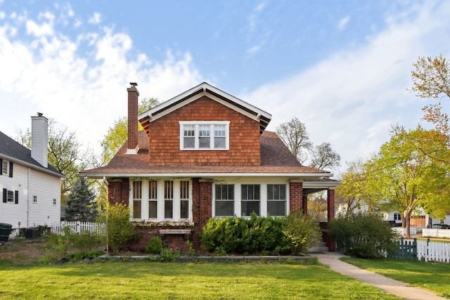 view of front of home with brick siding, fence, a chimney, and a front yard