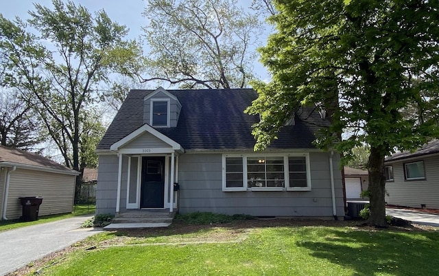 cape cod house featuring roof with shingles, central AC, and a front lawn
