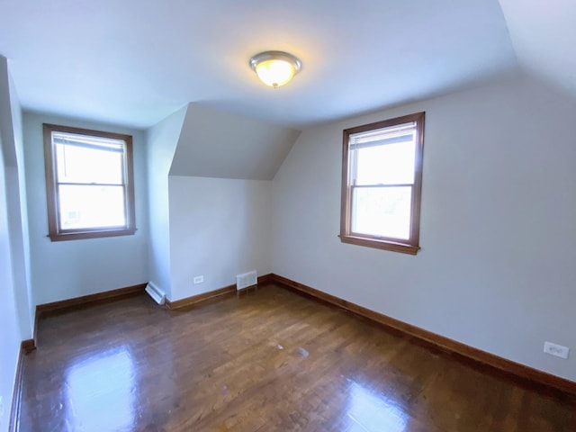 additional living space featuring a wealth of natural light, vaulted ceiling, wood finished floors, and visible vents