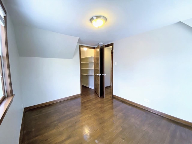 additional living space with baseboards, wood finished floors, and lofted ceiling