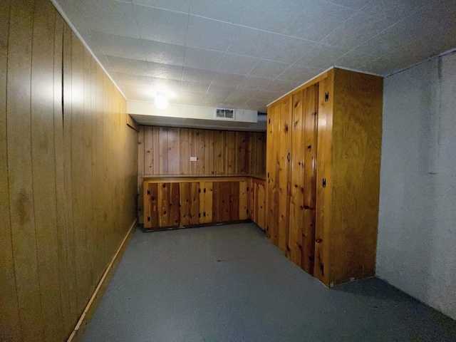 finished basement featuring carpet, wood walls, and visible vents