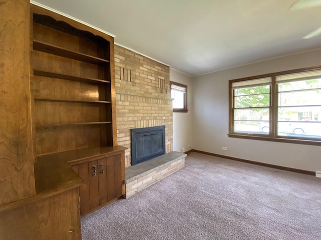 unfurnished living room with baseboards, ornamental molding, carpet floors, and a fireplace