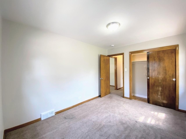 unfurnished bedroom with carpet floors, baseboards, visible vents, and a closet