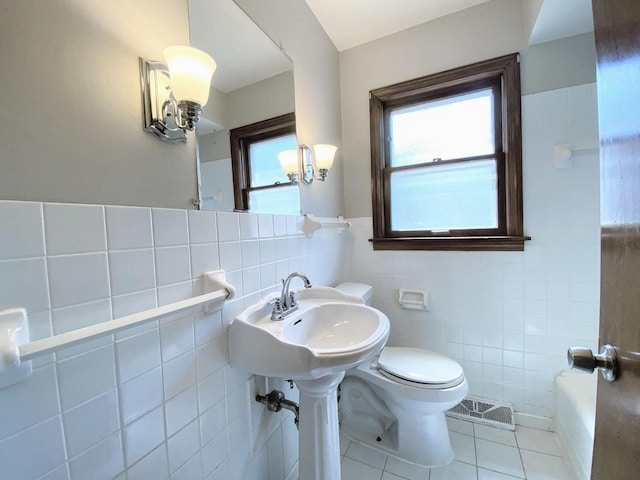 bathroom with a washtub, visible vents, tile walls, tile patterned flooring, and toilet