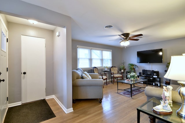 living area with baseboards, ceiling fan, light wood-style flooring, and visible vents