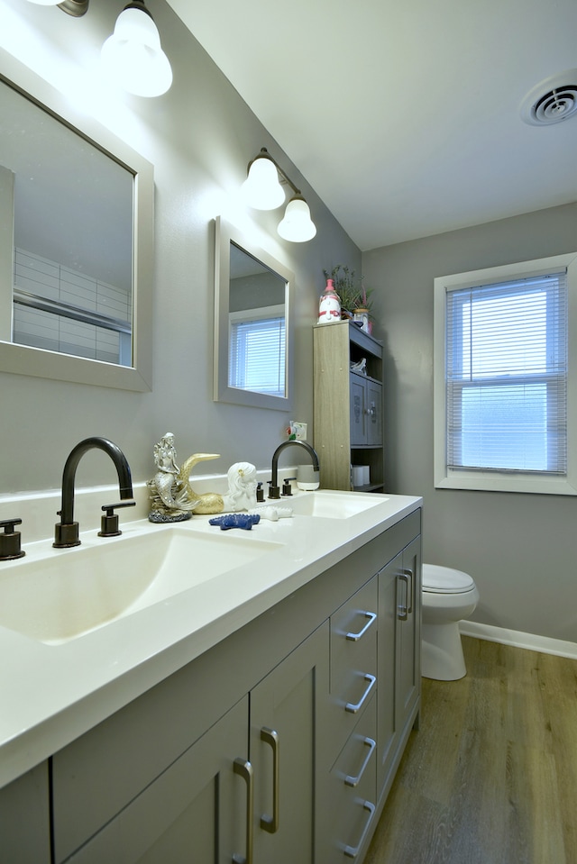 bathroom featuring toilet, visible vents, a sink, and wood finished floors