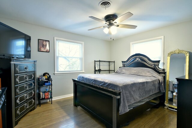 bedroom with visible vents, wood finished floors, and multiple windows