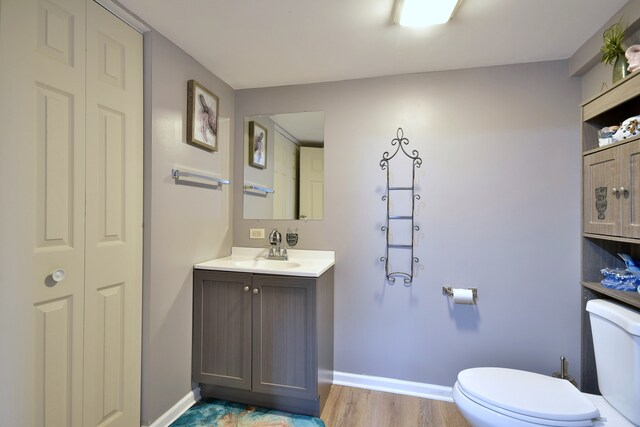 bathroom with toilet, baseboards, wood finished floors, and vanity