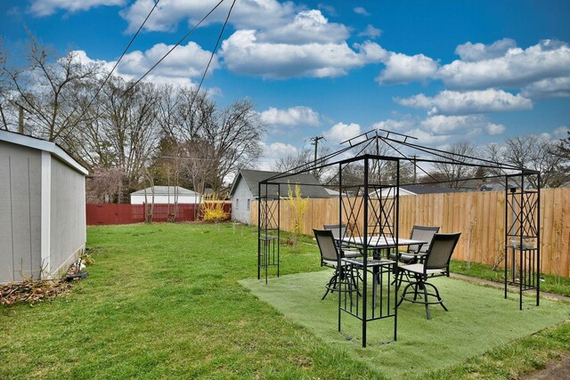 view of yard featuring a gazebo, a fenced backyard, and a storage unit