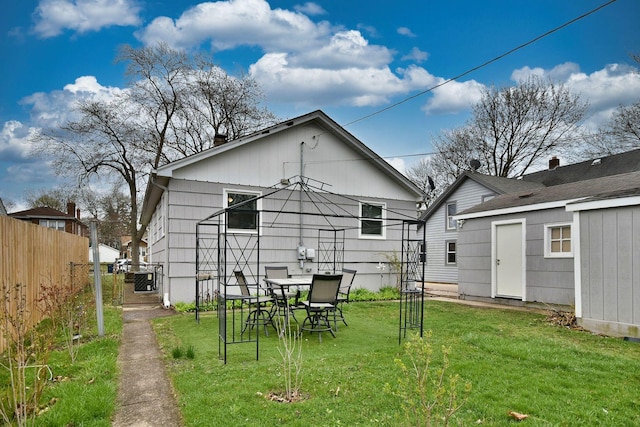 rear view of property featuring a lawn, a storage shed, fence, and an outbuilding