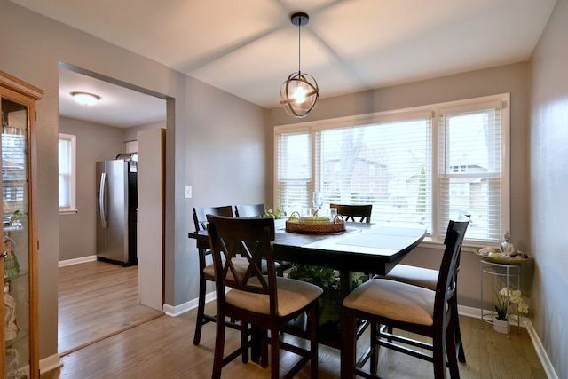 dining space featuring light wood-type flooring and baseboards
