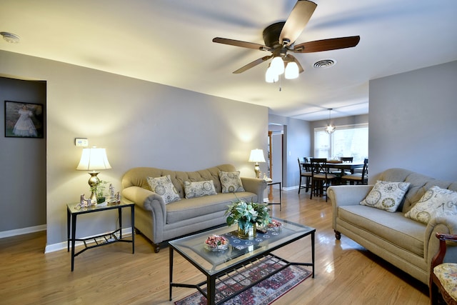 living room with baseboards, a ceiling fan, light wood-style flooring, and visible vents