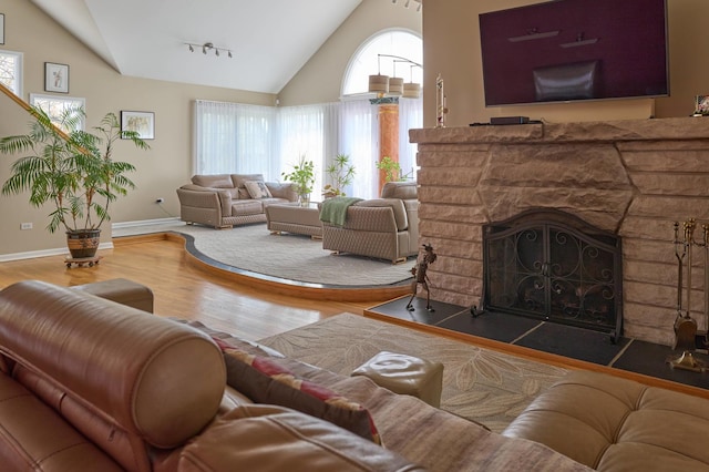 24270 N Forest Dr, Lake Zurich, IL 60047 - living room featuring wood finished floors, high vaulted ceiling, baseboards, rail lighting, and a stone fireplace