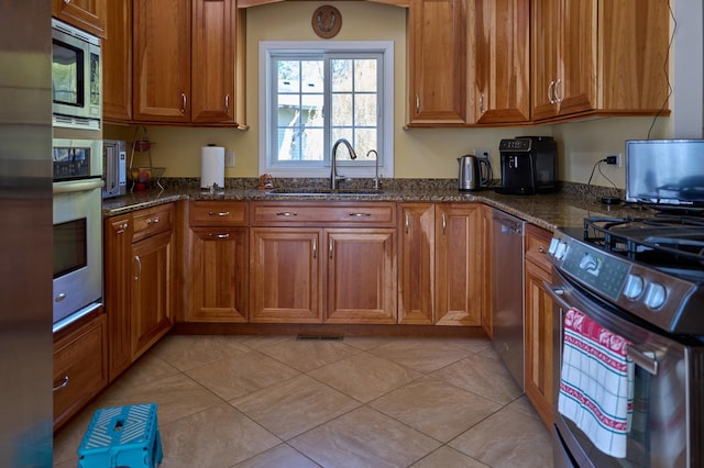 24270 N Forest Dr, Lake Zurich, IL 60047 - kitchen with appliances with stainless steel finishes, a sink, brown cabinets, dark stone countertops, and light tile patterned floors