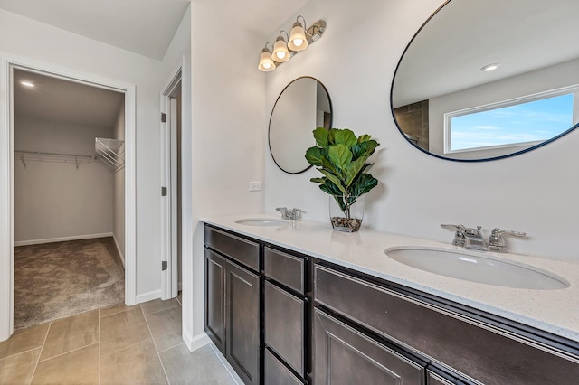 bathroom featuring double vanity, a sink, a walk in closet, and tile patterned floors
