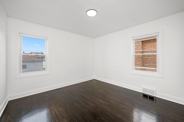 empty room with baseboards, dark wood-type flooring, and visible vents