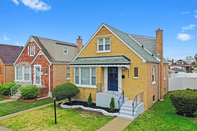 bungalow featuring a chimney, a front lawn, and brick siding