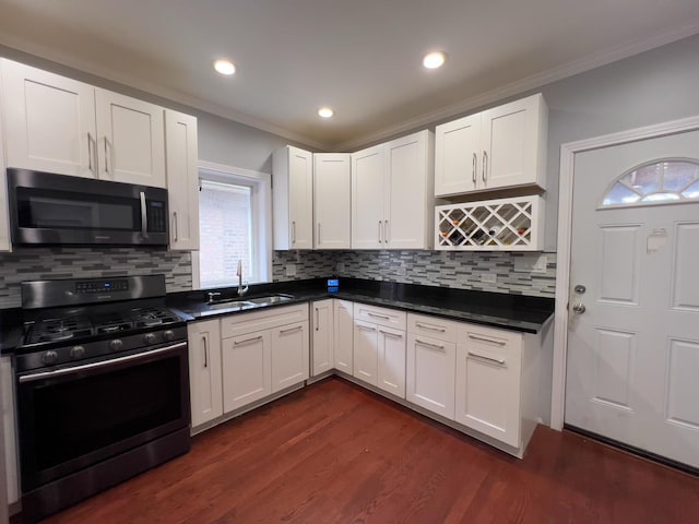 kitchen with a sink, white cabinetry, gas stove, and ornamental molding