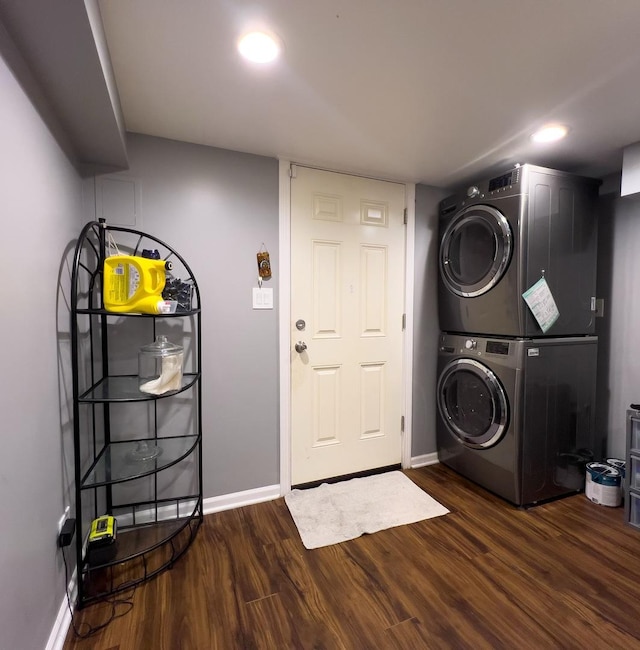 washroom featuring dark wood-type flooring, laundry area, baseboards, and stacked washer / dryer