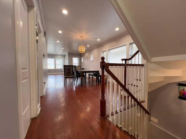 interior space featuring ornamental molding, dark wood-type flooring, recessed lighting, a notable chandelier, and an upstairs landing