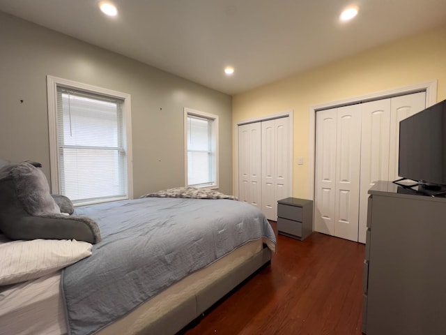 bedroom with two closets, recessed lighting, and dark wood finished floors