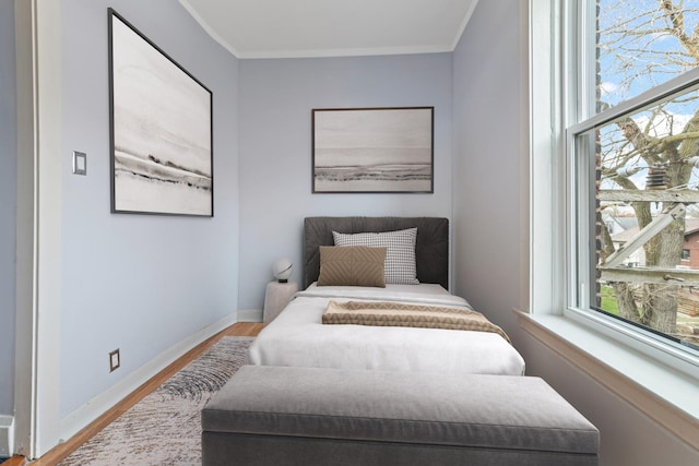bedroom featuring baseboards, ornamental molding, and wood finished floors