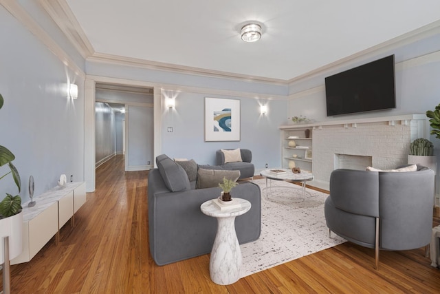 living room featuring crown molding, a brick fireplace, and wood finished floors
