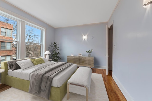 bedroom with baseboards, ornamental molding, and wood finished floors