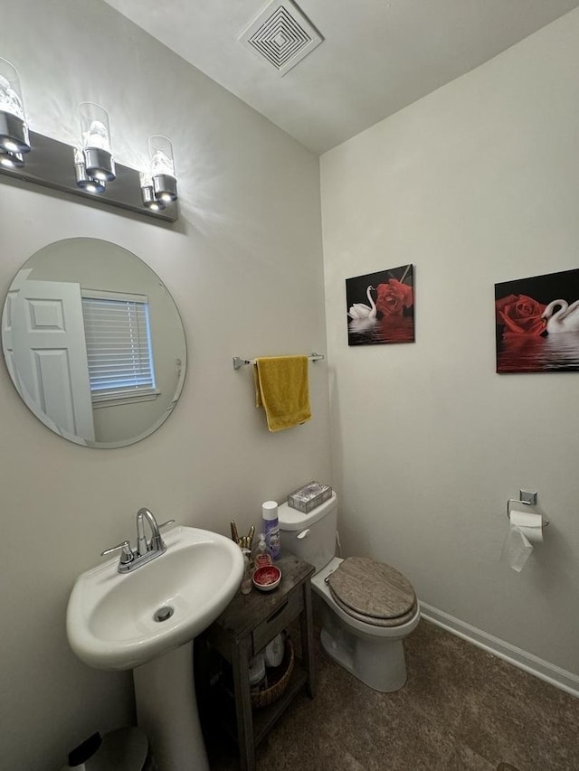 half bathroom with visible vents, a sink, baseboards, and toilet