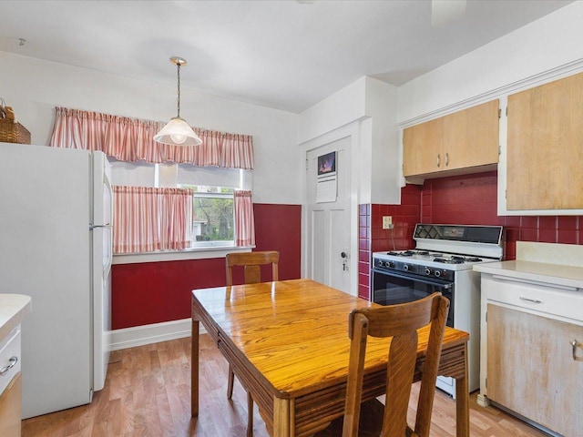kitchen featuring white appliances, light wood-type flooring, light countertops, backsplash, and decorative light fixtures