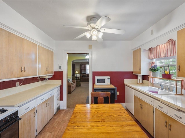kitchen with a ceiling fan, gas range, light countertops, a sink, and white microwave