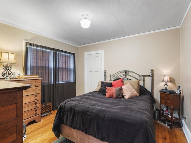bedroom with crown molding, baseboards, and light wood-style flooring