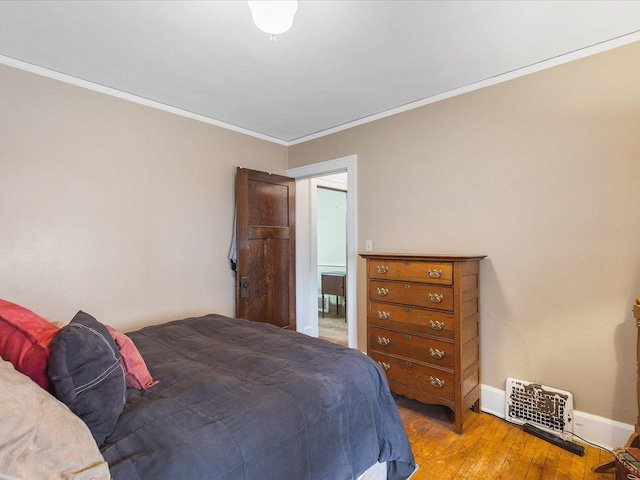bedroom featuring baseboards, ornamental molding, and hardwood / wood-style flooring