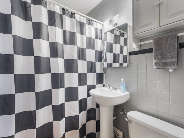 bathroom featuring toilet, tile walls, decorative backsplash, and a shower with shower curtain