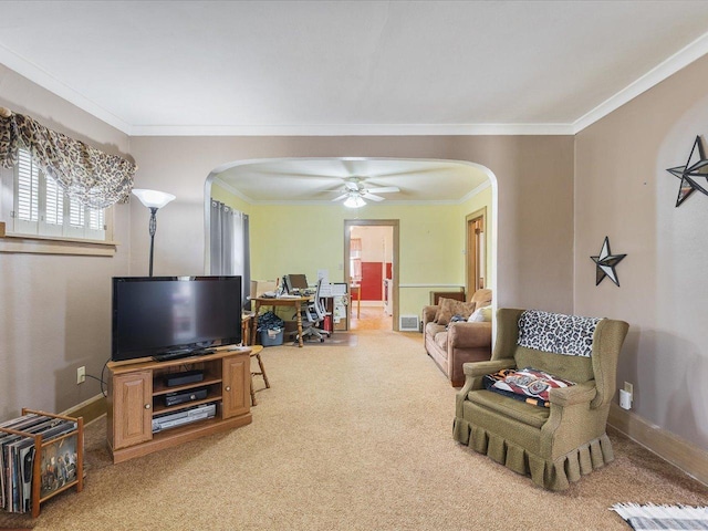 living room featuring ceiling fan, arched walkways, baseboards, ornamental molding, and light carpet