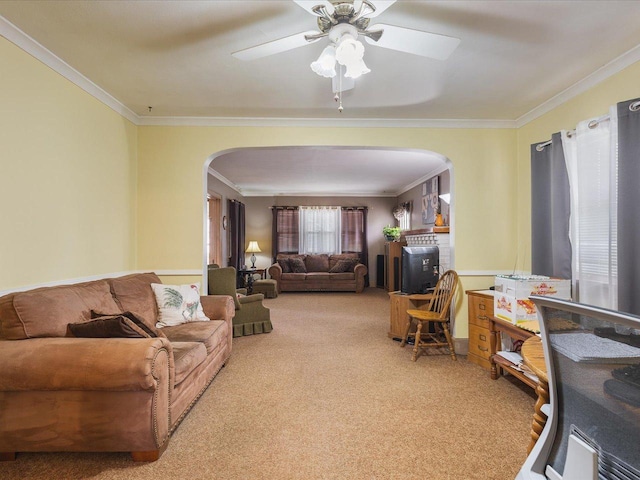carpeted living area with crown molding, arched walkways, and a ceiling fan